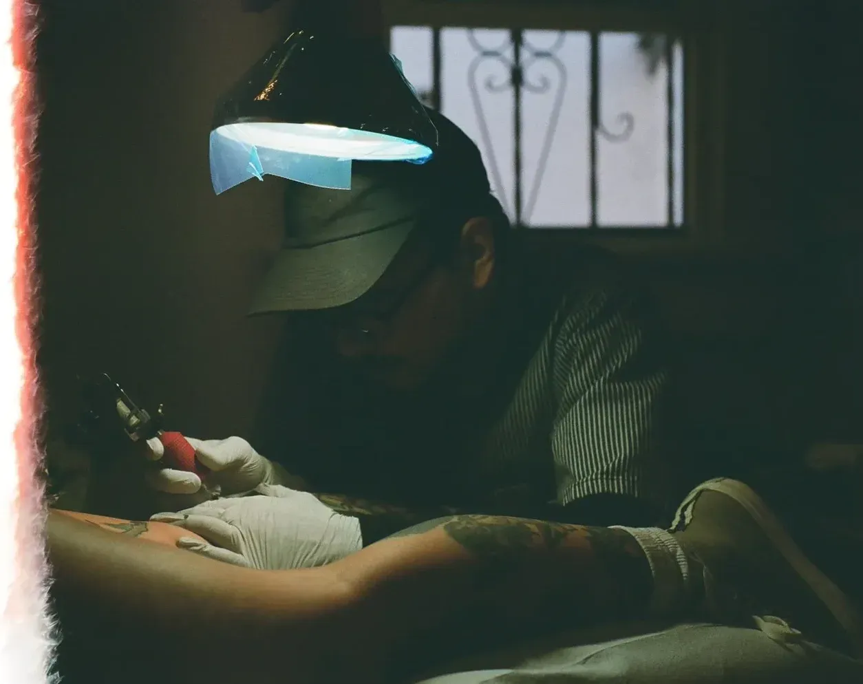 Artist tattooing under warm studio light